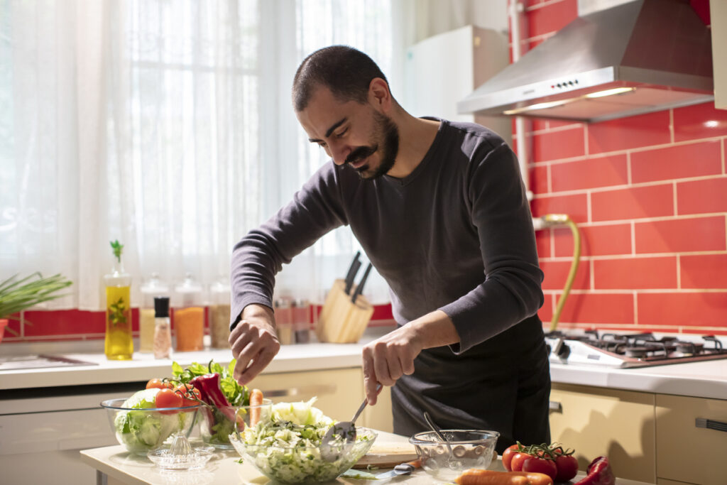Man preparing a balanced meal of vegetables and proteins 